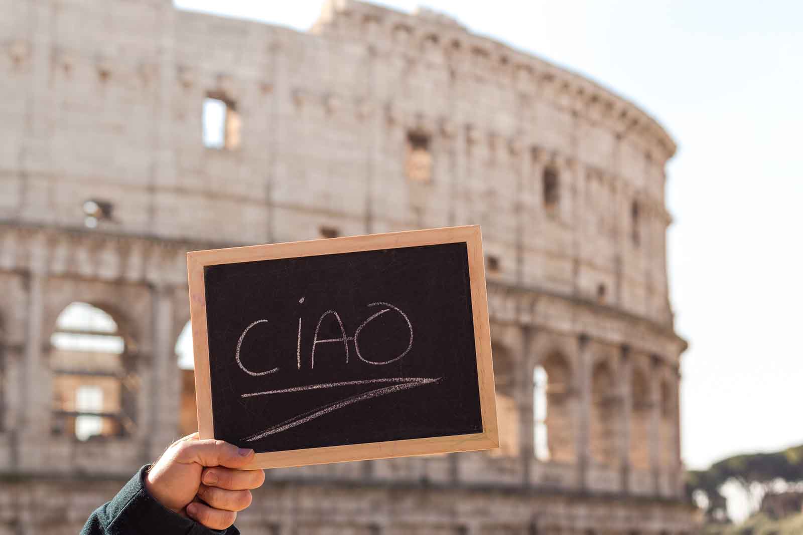 the word ciao on a chalkboard in front of the colosseum