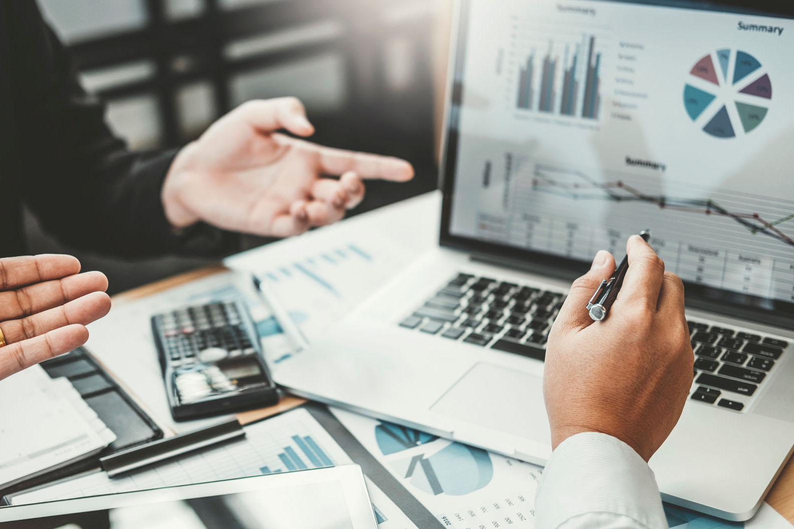 two people looking over a laptop with charts and numbers on the screen