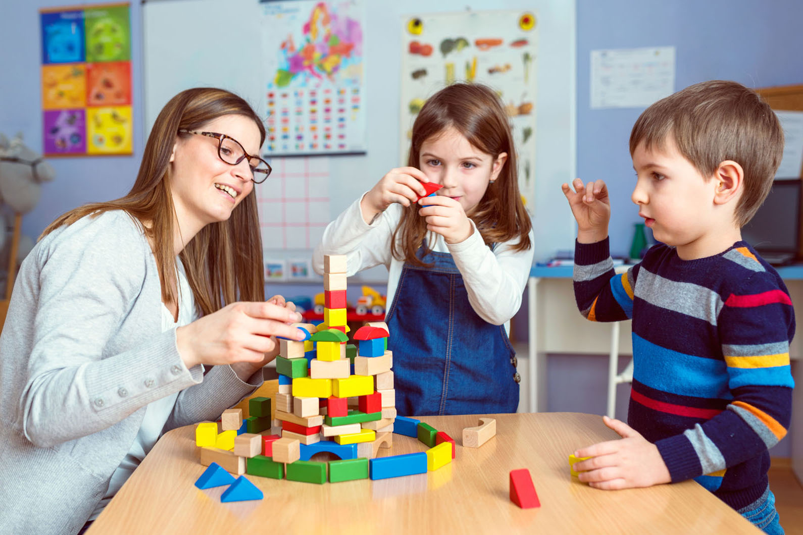 two children playing blocks with a teacher