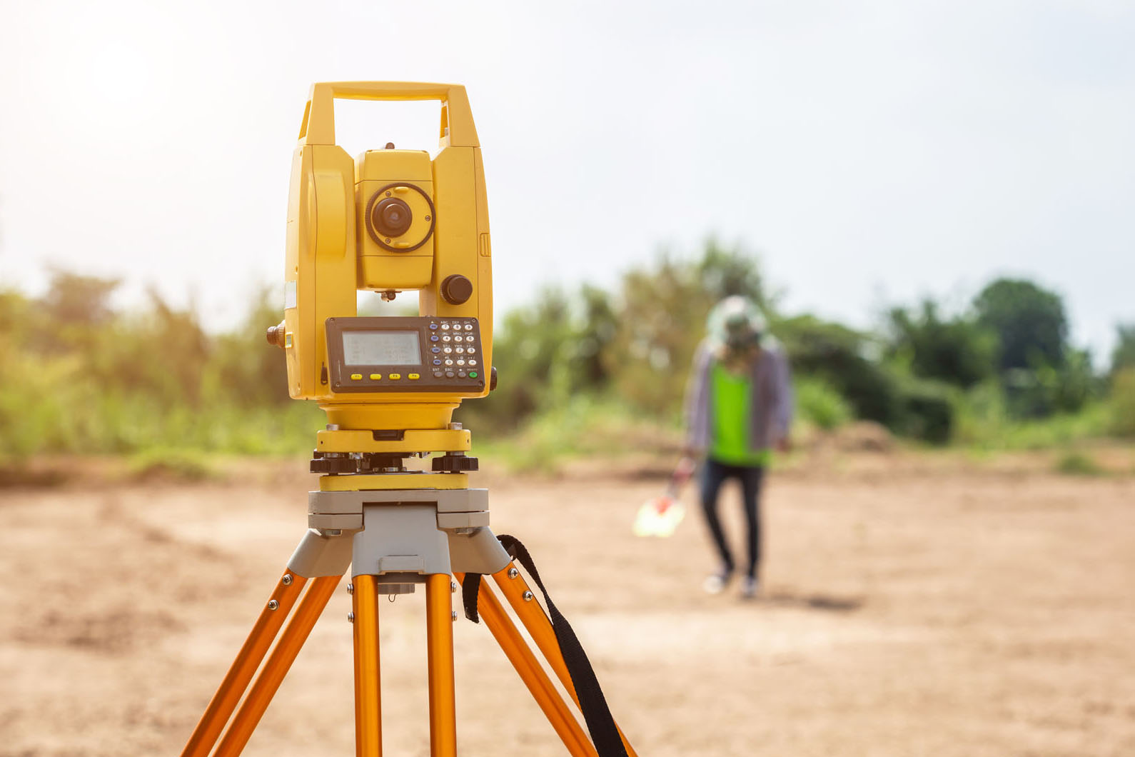 land survey tool in focus with a person out of focus far away